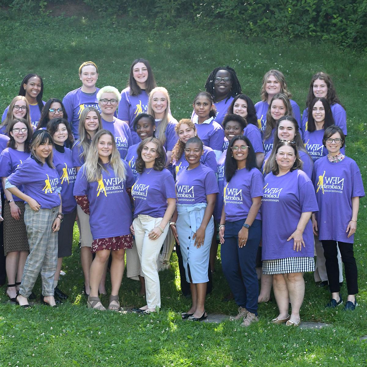 Photo of a group of women in purple NEW 领导 t-shirts posing for a photo outside